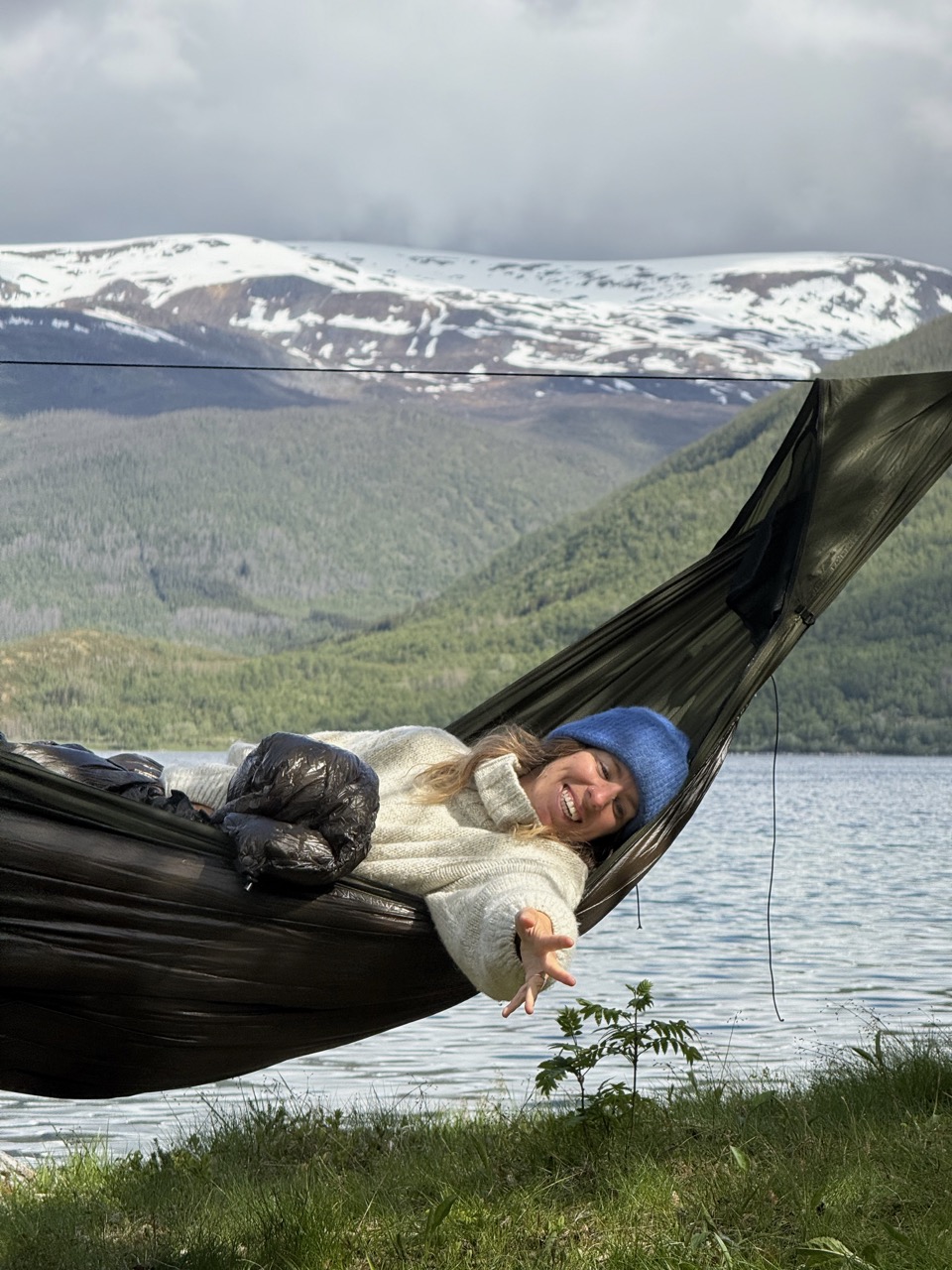 The maker rigging a Momo Jord Hammock between birch trees above a fjord